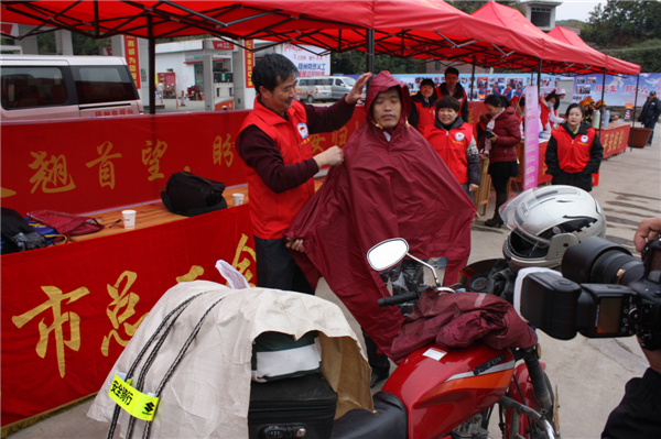 梧州市總工會(huì)的黨員義工們?cè)谑袞|出口春運(yùn)服務(wù)站助力“摩托大軍”平安返鄉(xiāng)，幫助他們檢查車(chē)輛和行李，穿上雨衣。--黃賀峰攝.j